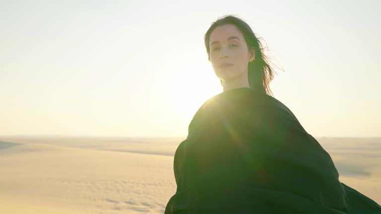 Portrait of Young beautiful girl in traditional Abaya dress on the dunes in the desert of Qatar. 4K Slow Motion