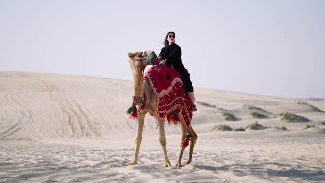 tourist woman riding camel at the desert