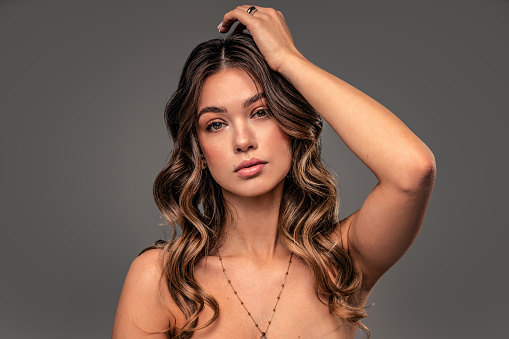 Beauty portrait of young attractive woman with delicate makeup and wavy long natural hair. Girl looking at the camera.