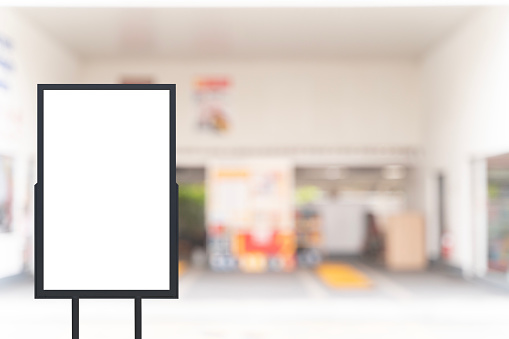 A billboard stands in front of a car repair shop. The billboard is empty. There are no text or pictures. The car repair shop is a small car repair shop. Clipping path.