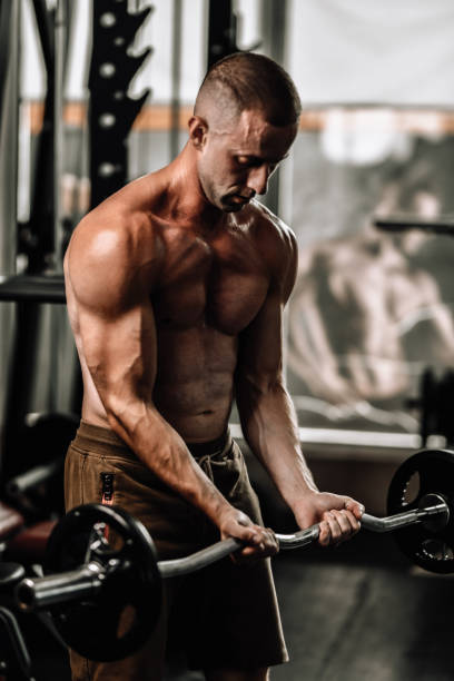 istock Athletic Male Doing EZ Bar Curls In Gym 2004957527