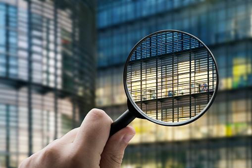 A magnifying glass focusing on an office building exterior at night