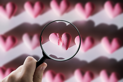 A magnifying glass focusing on a broken heart