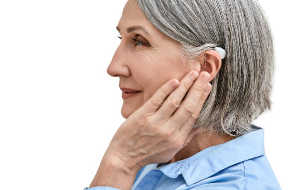 istock Middle-age woman with hearing impairment using hearing aid, side view. Hearing solutions for deafness people 2005000550