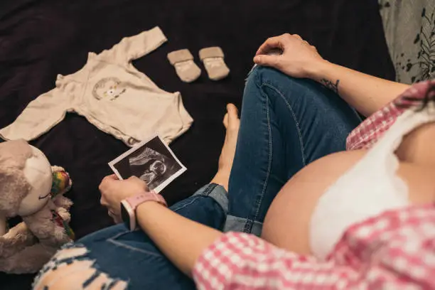 Overhead View of Pregnant Woman Dreaming of Future Baby. Overhead view of a pregnant woman dreaming of her future baby, looking at an ultrasound.