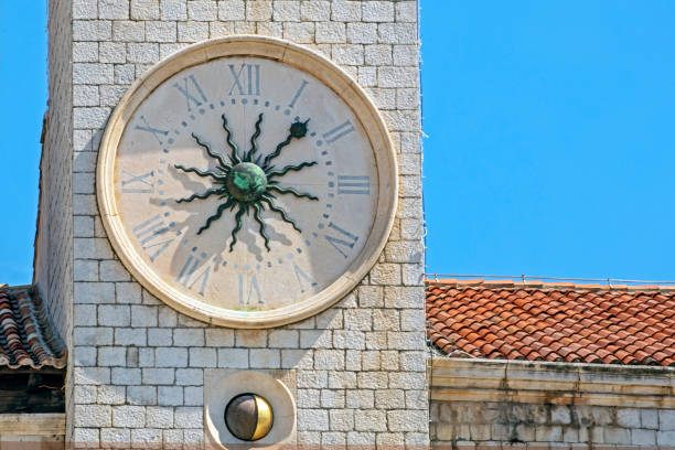 antique clock with a copper sculpted sun in the middle against the sky