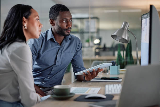 Collaboration, computer and tablet with business people in office together for planning or project management. Feedback, teamwork or technology with employee man and woman in workplace for research