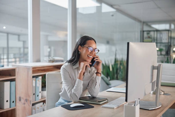 Phone call, business and woman with a computer, conversation and smile with project and talking. Person, office and employee with pc and worker with joy and laughing with communication and discussion