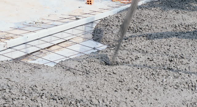 Close up of concrete pouring directly on the ground and reinforced with steel rebars