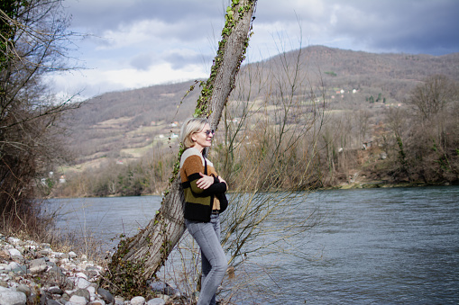 mature blond woman in nature by the river on vacation