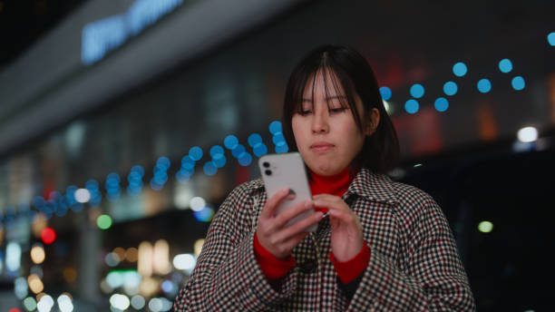 istock Woman using her smart phone in city at night 2005031781