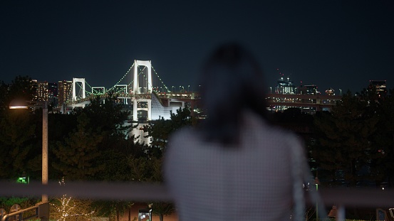 A woman is looking at the cityscape of Tokyo from Tokyo bay Odaiba.