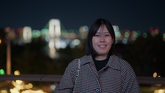 A portrait of an Asian woman in the city at night.
