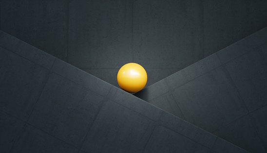 Balance and harmony concept. Yellow sphere over grey concrete wall background. Horizontal composition.