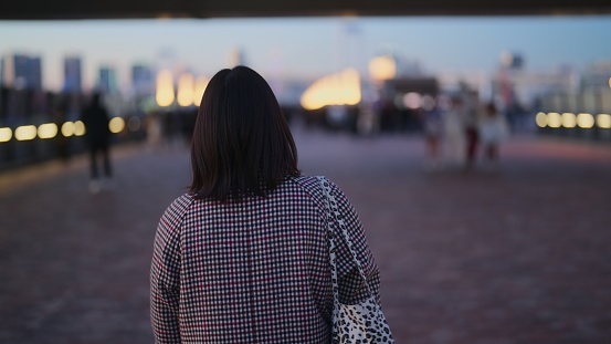 A woman is walking in the city Odaiba Tokyo at night.