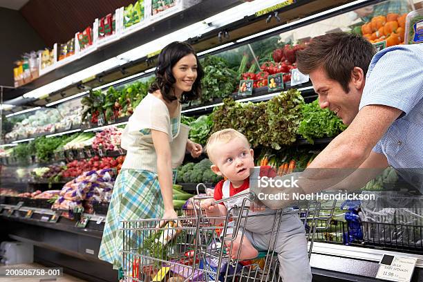 Pareja Joven Con Bebé Son En Supermercado Smilin Foto de stock y más banco de imágenes de Supermercado