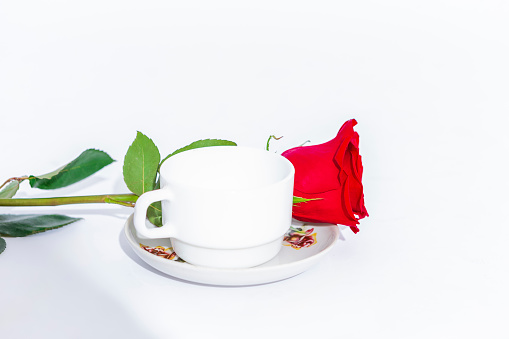 One Red Rose Flower Along with Set of White tea Cup and Plate over White.Horizontal Image
