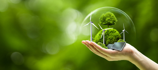 Business hand holds green globe with tree, wind turbine and solar powered for ESG, CO2 and Net Zero concept for sustainable corporate environmental development. Save the environment or Earth Day of a green company