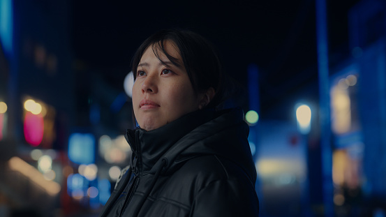 A portrait of an Asian woman in the city at night.