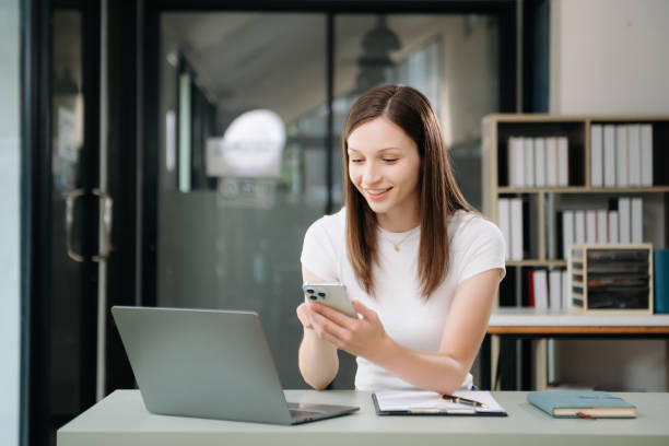 istock Beautiful woman using laptop and tablet while sitting at her working place. Concentrated 2005099760