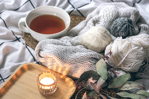 istock Cozy composition with a cup of tea, a candle and knitted elements on a blanket. 2005101412