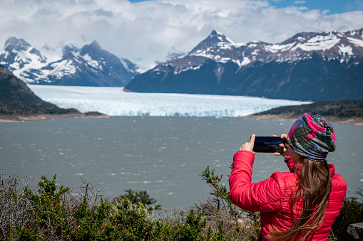 Tourist taking a photo of the imposing Perito Moreno glacier in Argentina. Woman walking the walkways of the Perito Moreno National Park. Young woman on vacation in southern Argentina
