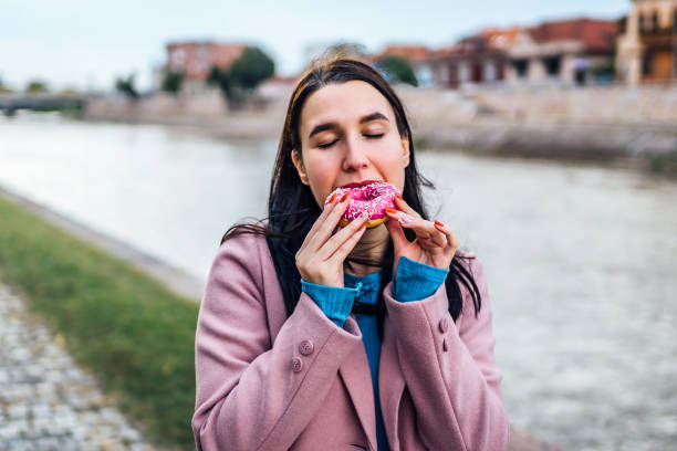 istock Woman enjoying eating donut by the river 2005122785