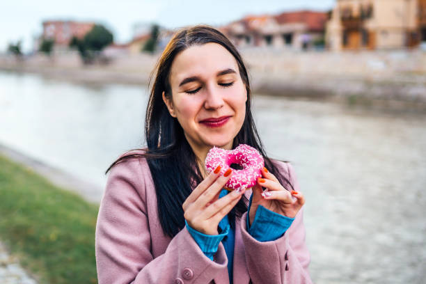 istock Woman enjoying eating donut by the river 2005123551