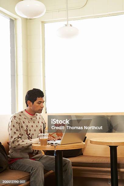 Junger Mann Mit Eiskaffee Mit Laptop Im Café Stockfoto und mehr Bilder von Indianischer Abstammung - Indianischer Abstammung, Laptop, Laptop benutzen