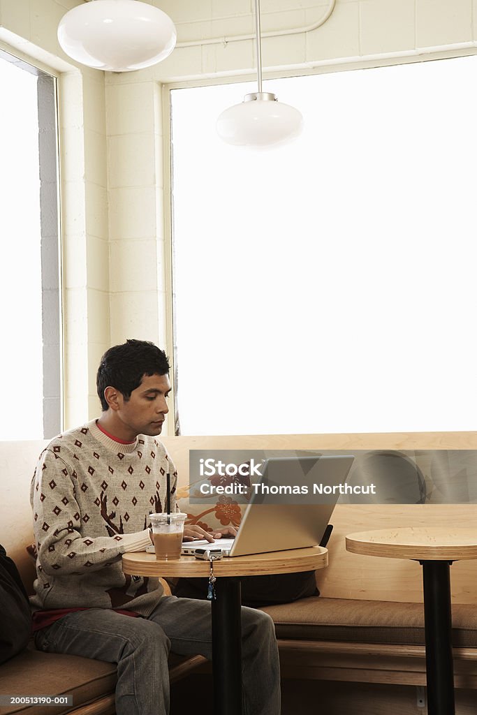 Jeune homme avec café glacé à l'aide d'un ordinateur portable dans un café - Photo de Ordinateur portable libre de droits