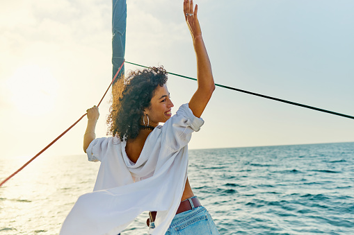 Young female tourist enjoys getting away from it all and sailing out on the open ocean towards the setting sun.