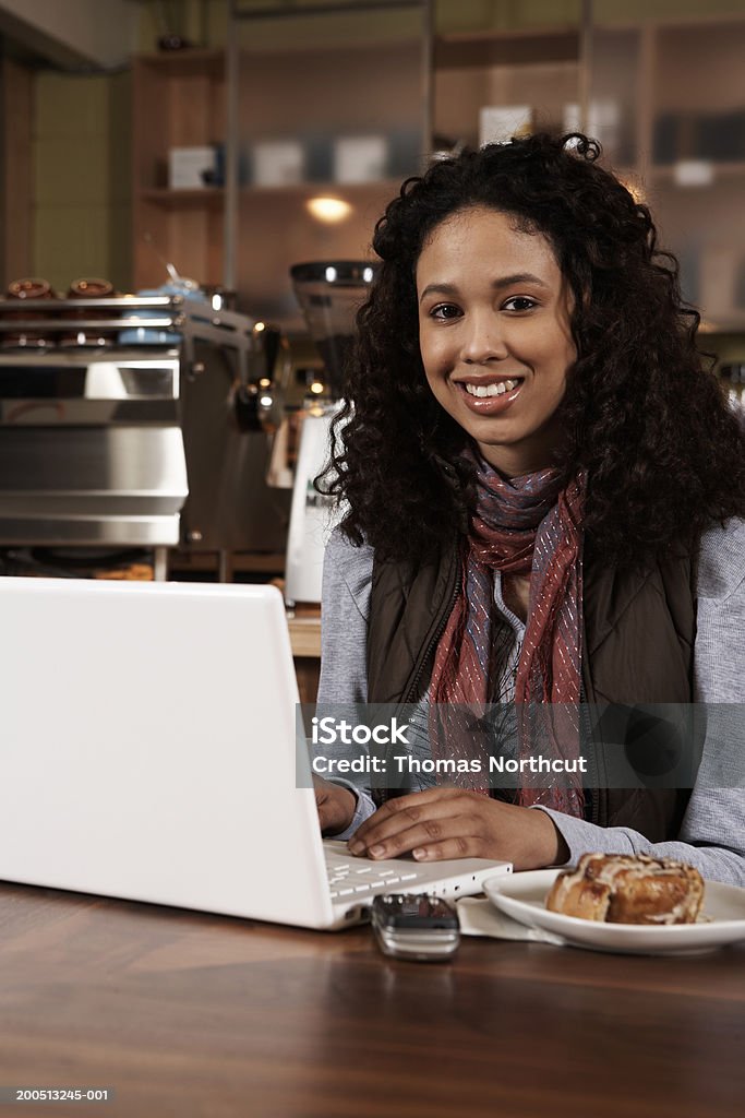 Ragazza adolescente (16-18) usando il portatile al tavolo al bar - Foto stock royalty-free di 16-17 anni