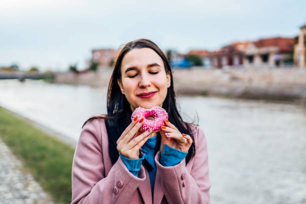 istock Woman enjoying eating donut by the river 2005142743