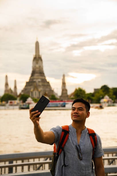 istock man taking selfie when  Exploring Wat Arun Temple at sunset in Bangkok, Thailand 2005161326