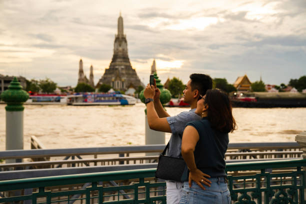 man taking selfie when  Exploring with view Wat Arun Temple at sunset in Bangkok, Thailand