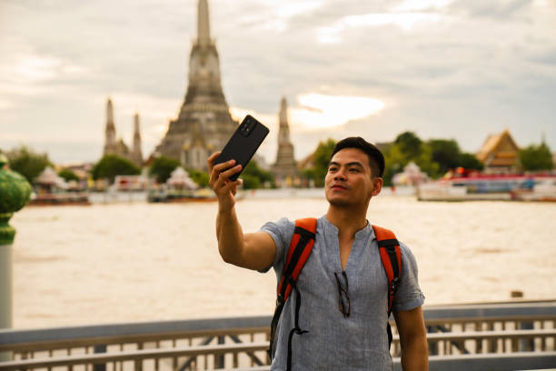 istock man taking selfie when  Exploring Wat Arun Temple at sunset in Bangkok, Thailand 2005162318