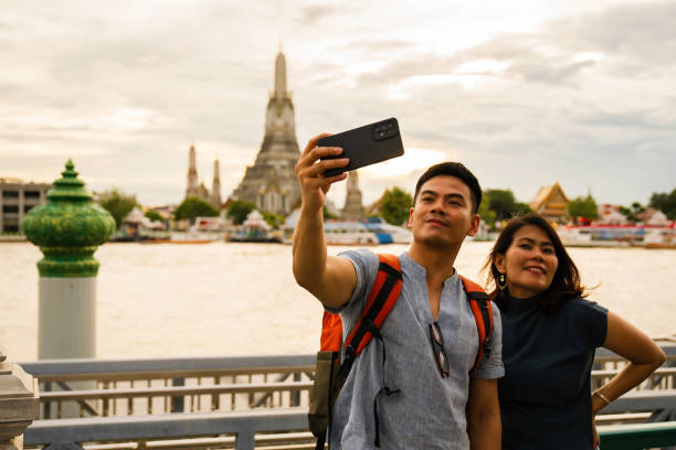 istock man taking selfie when  Exploring with view Wat Arun Temple at sunset in Bangkok, Thailand 2005162400