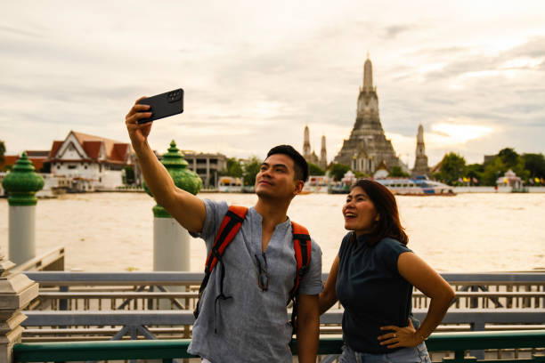 istock man taking selfie when  Exploring with view Wat Arun Temple at sunset in Bangkok, Thailand 2005162408
