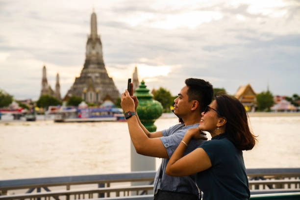 istock man taking selfie when  Exploring with view Wat Arun Temple at sunset in Bangkok, Thailand 2005163031