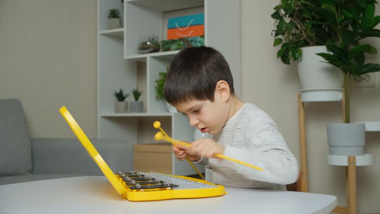 A six-year-old child plays a metallophone, a percussion musical instrument