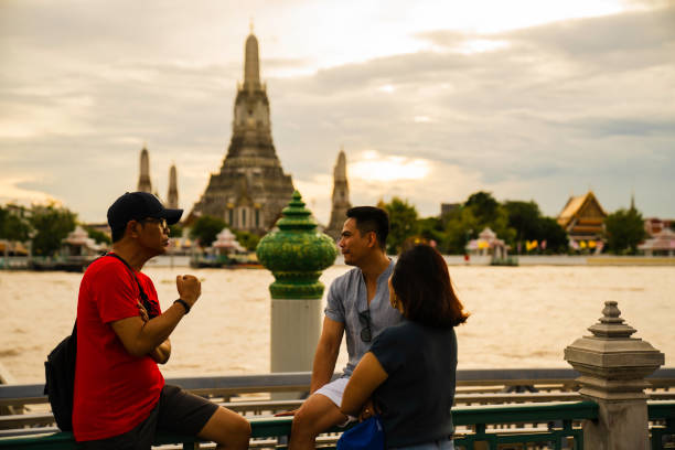 Portrait of multiethnic friends enjoying spending time making happy memories together outdoors with with view Wat Arun Temple at sunset in Bangkok, Thailand