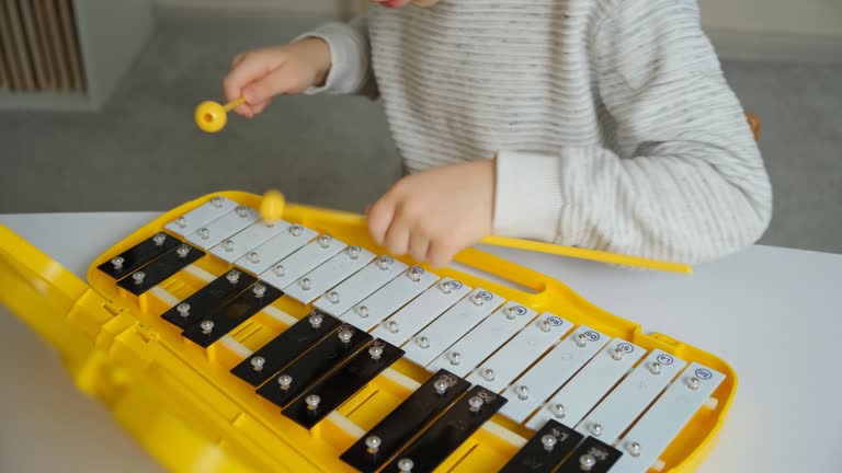 Playing with sticks on a metallophone. Child playing percussion musical instrument, hands close-up