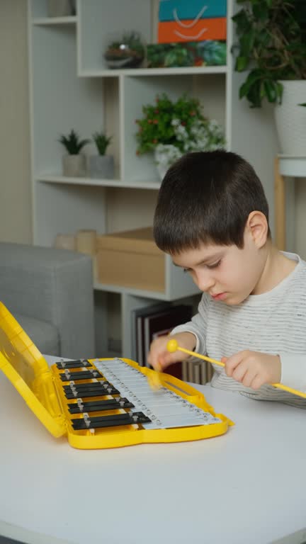 A six-year-old child plays a metallophone, a percussion musical instrument