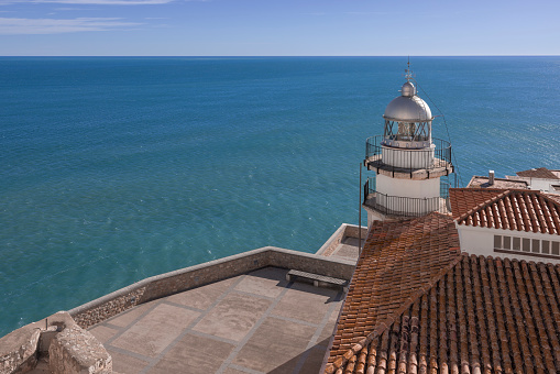 The lighthouse of Peniscola in front of the blue sea and sky.