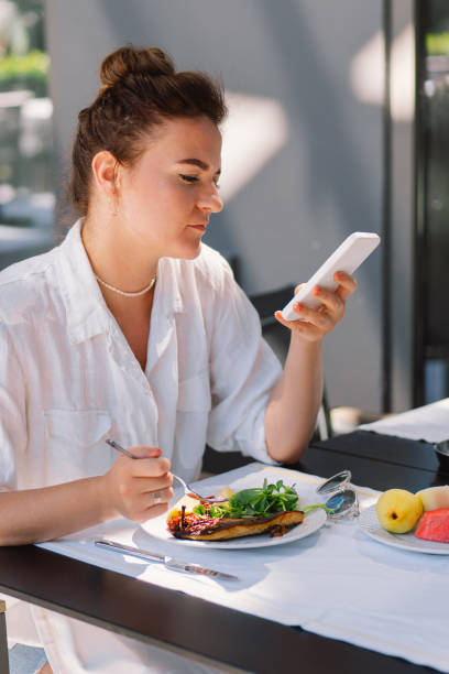 istock A woman uses a phone and eats 2005198162