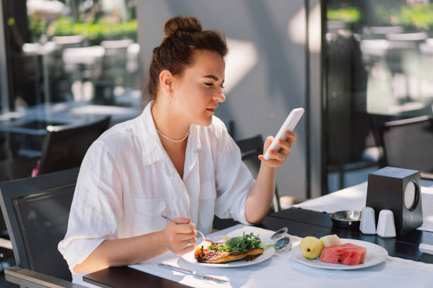 istock A woman uses a phone and eats 2005198166