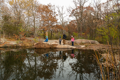 Father and three children exploring near an old granite quarry pond. Taken on an autumn day at Quarry Park in Minnesota, USA.