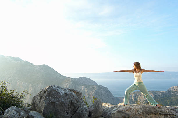 Young woman performing stretching exercises on rock near sea Croatia warrior 2 stock pictures, royalty-free photos & images