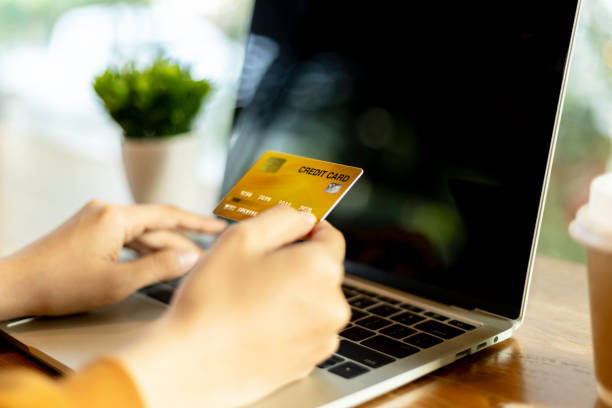 istock Hand holding credit card and using laptop. Online shopping, e-commerce, internet banking, spending money, work from home concept 2005220940