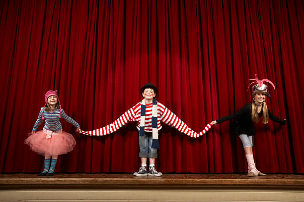 Two girls and boy (6-10) in costume taking bow on stage, smiling  curtain call stock pictures, royalty-free photos & images